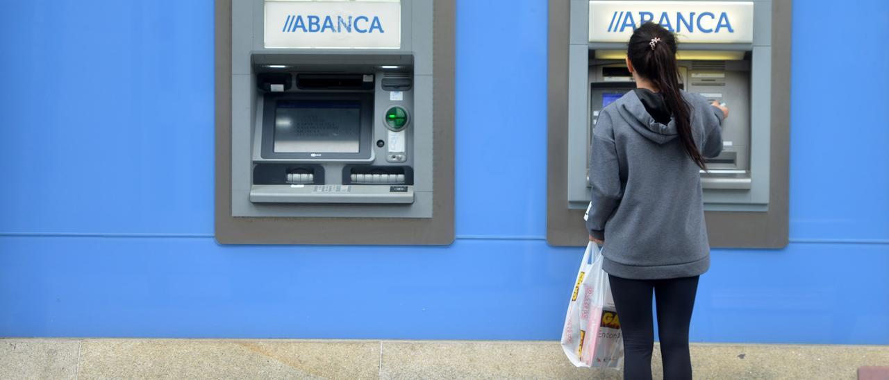 Una mujer saca dinero de un cajero automático de Abanca