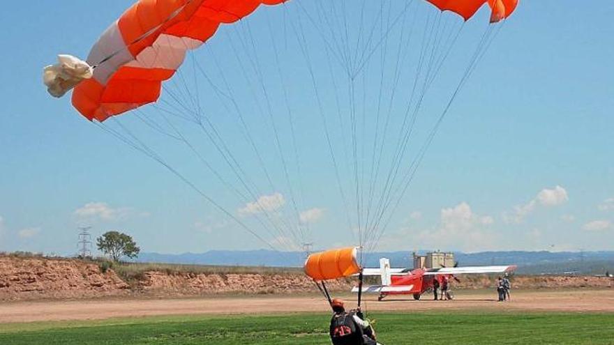 Un paracaigudista aterrant a l&#039;aeròdrom, amb l&#039;avioneta al fons