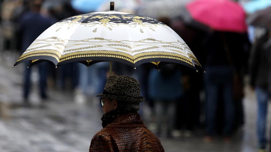 Una mujer se protegue de la lluvia con un paraguas.