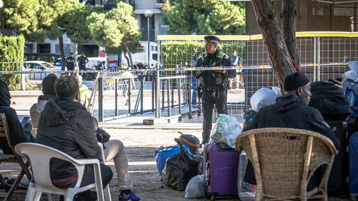 Un grupo de personas sin hogar mira a un agente de la Guardia Urbana de Barcelona durante el desalojo del campamento del Parque de Joan Miró, el pasado octubre