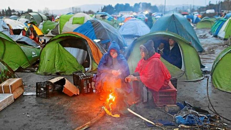 Un grup de refugiats s&#039;escalfen a la frontera entre Grècia i Macedònia