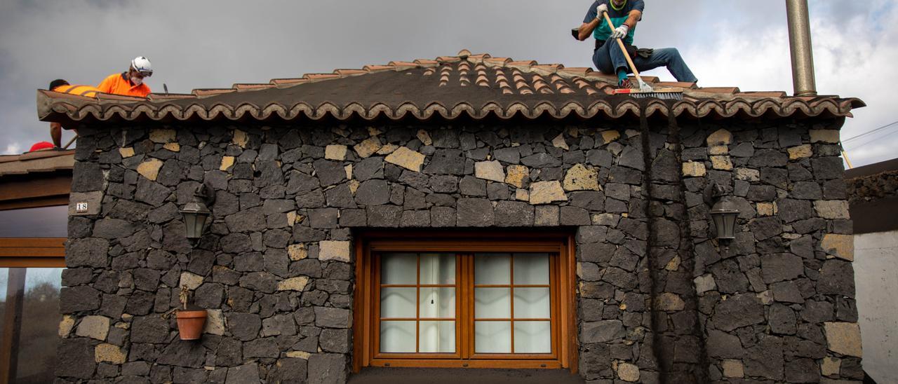 Voluntarios retiran las cenizas del volcán acumuladas en una vivienda en La Palma.