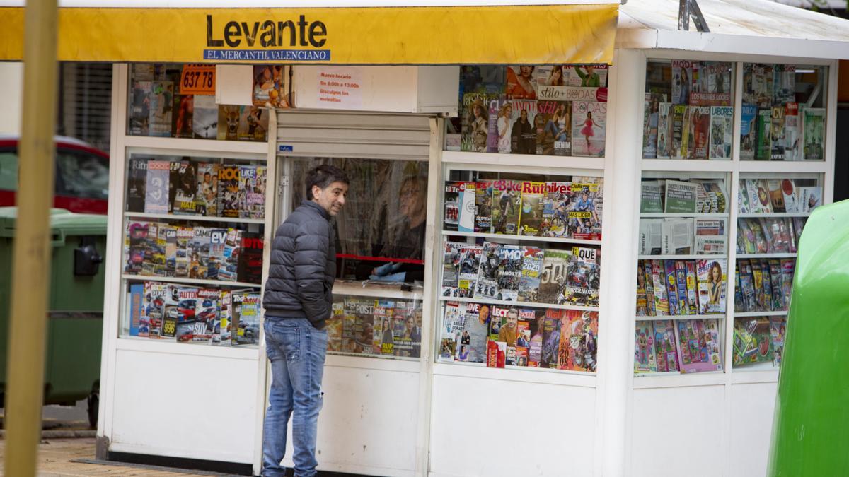 Un hombre compra su periódico en un quiosco.