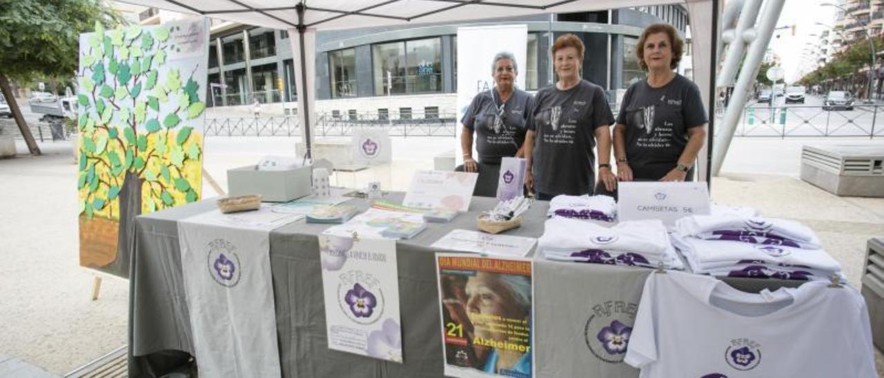 res voluntarias de Afaef atienden la mesa informativa de Vara de Rey, donde está instalado el árbol de los recuerdos, lleno ya de hojas