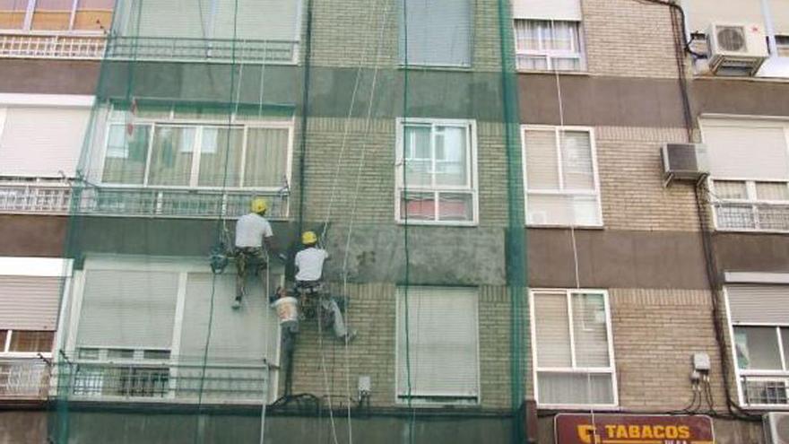 Obreros trabajando en la reforma de una fachada.