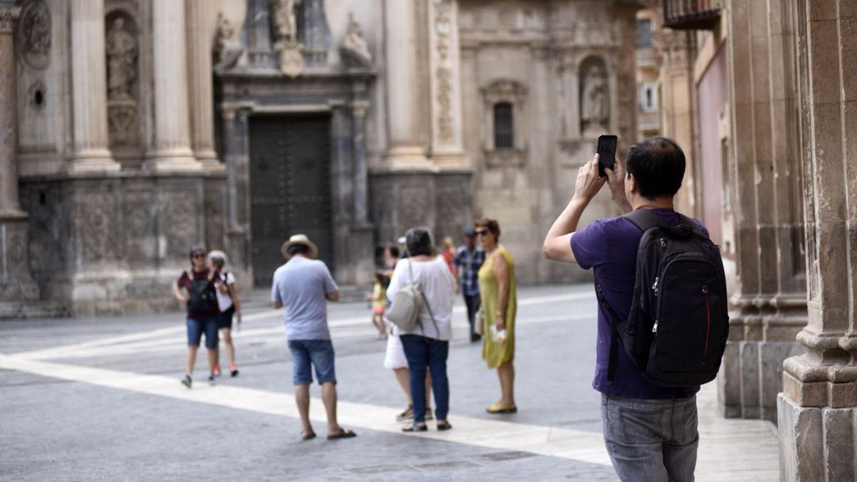 Un turista fotografía la fachada de la Catedral de Murcia. | ISRAEL SÁNCHEZ