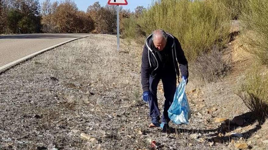 Un hombre recoge botellas de la cuneta de la carretera.