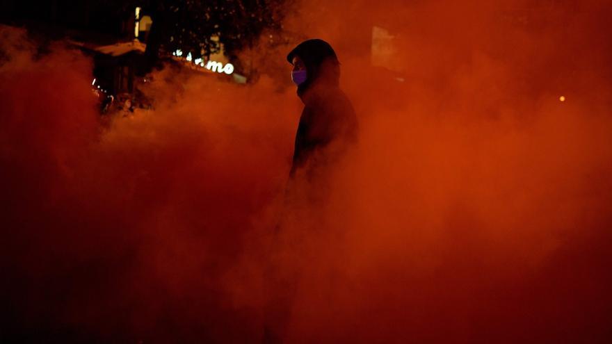 Manifestantes lanzan bengalas y objetos contra la policía que protege la sede de la Guardia Civil en Travesera de Gràcia de Barcelona