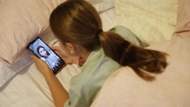 Una adolescent observa a l’habitació una ‘influencer’ a TikTok a través del telèfon mòbil. | LUIS TEJIDO / EFE