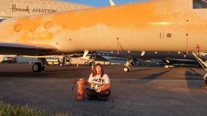 Una activista de Just Stop Oil se sienta en señal de protesta frente a jet privado que acaba de rociar de pintura.