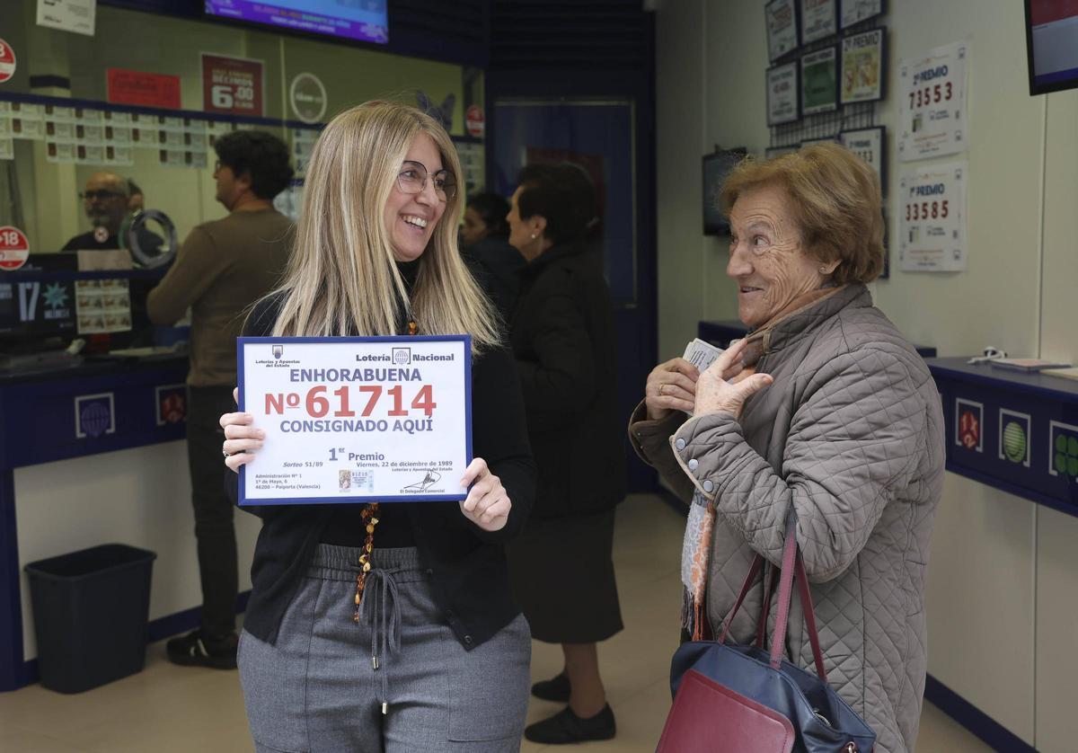 Cristina Piles con una vecina sujeta el primer premio que consiguieron en el sorteo de Navidad de 1989 y que aspiran a repetir.