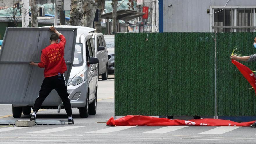 Treballadors amb mascaretes aixequen barreres a la ciutat de Wuhan