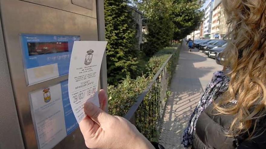 Una joven muestra el tique de la zona azul gratuita junto al parquímetro del parque Javellanos.