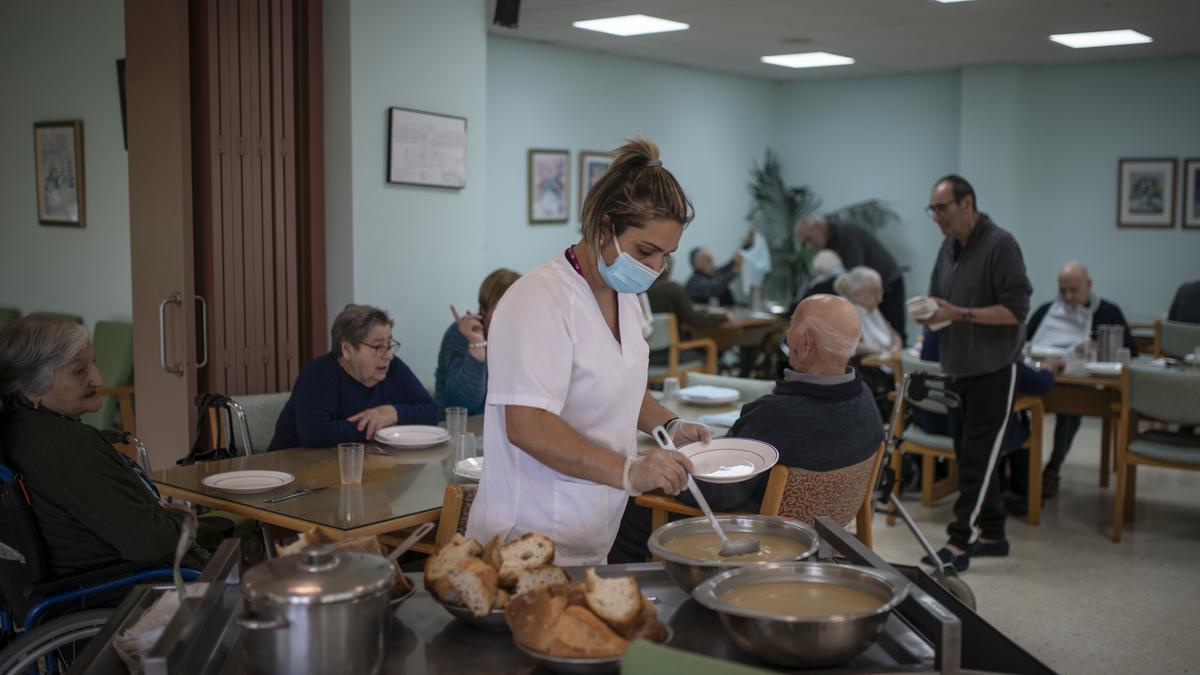 Una trabajadora sirve la comida la sopa en el comedor del pasillo primero izquierda.