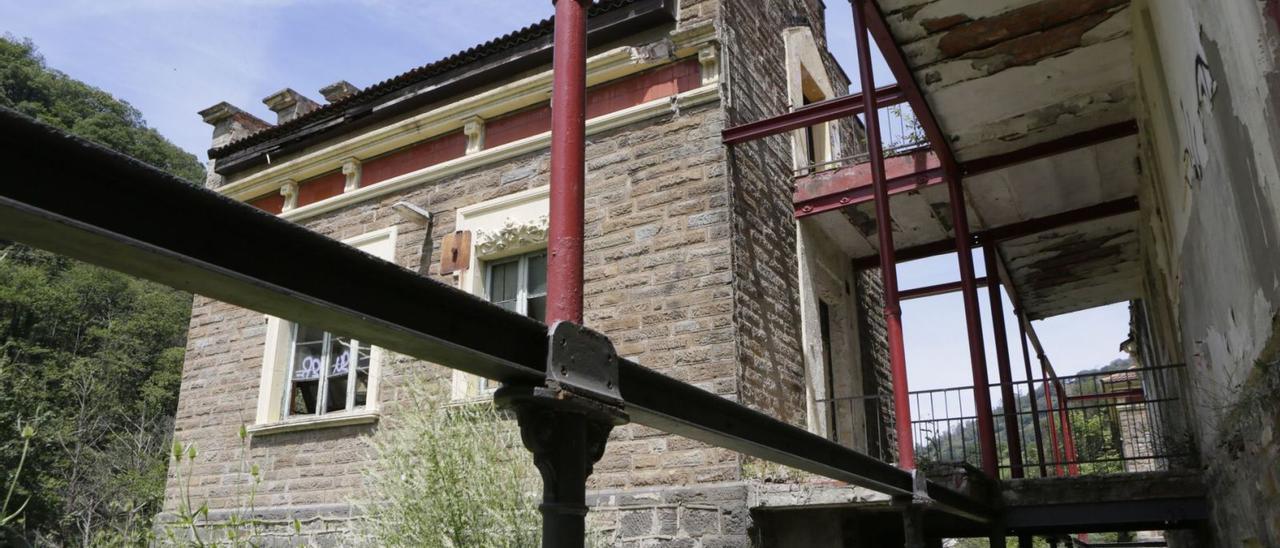 A la derecha, una de las galerías del sanatorio de Bustiello. Abajo, una pancarta exigiendo actuaciones en el enclave.