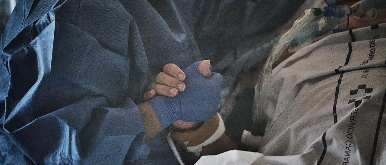 Un paciente coge la mano del sanitario que ha estado cuidándolo en el Hospital de La Candelaria, en una fotografía de archivo.