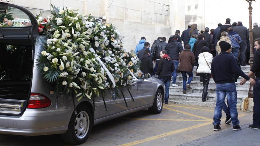 El coche fúnebre junto a los vecinos que entran a la iglesia