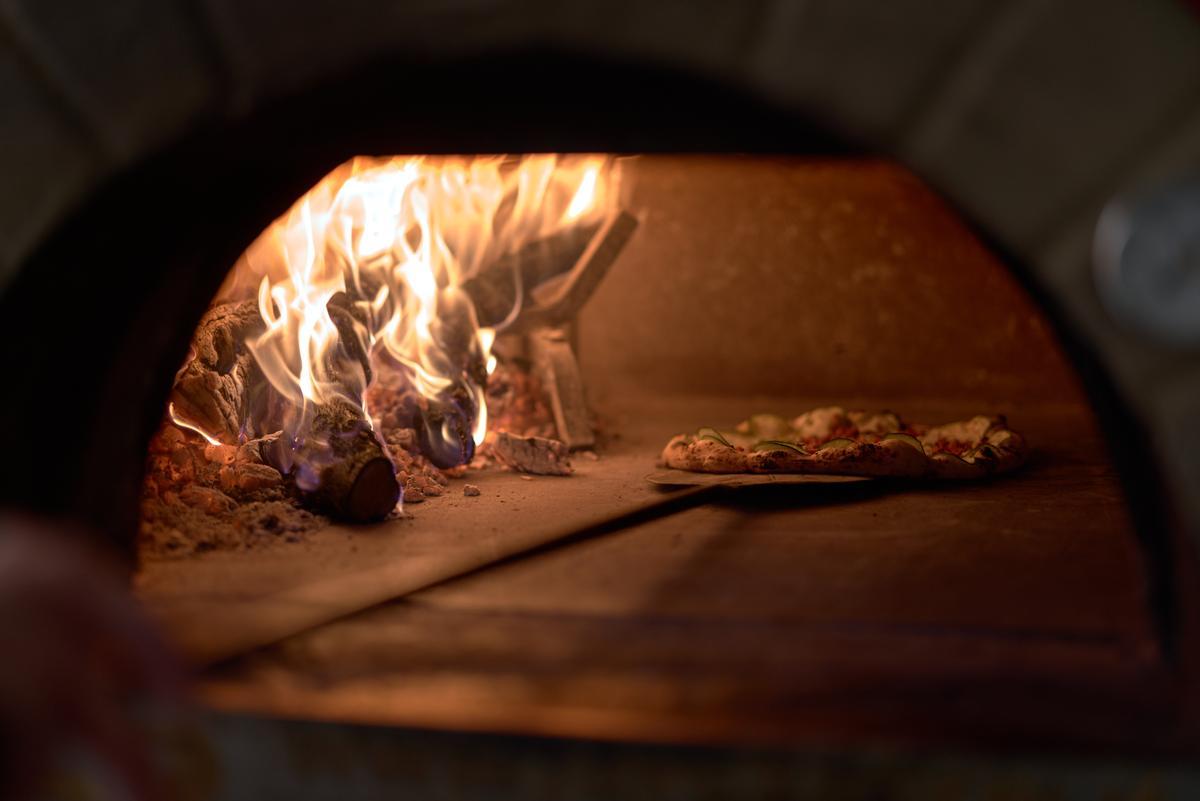 Una pizza, saliendo del horno de leña.