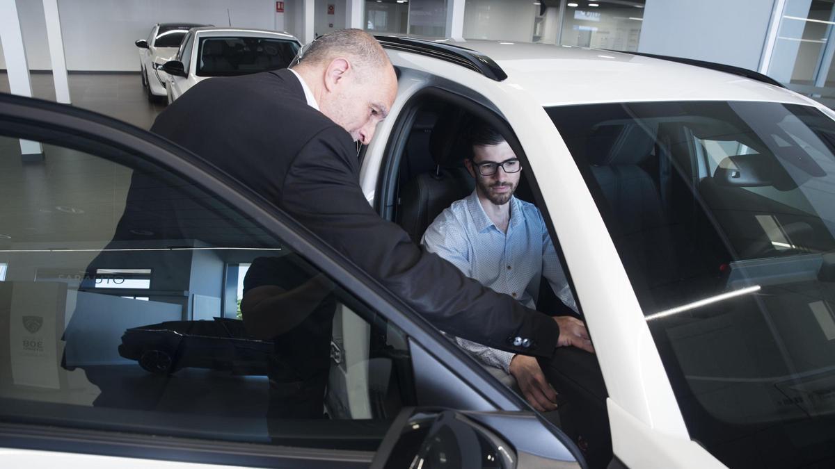 Un treballador d’un concessionari ensenya l’interior d’un cotxe a un client, en una imatge d’arxiu.