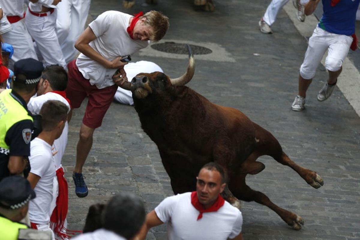 Un dels toros banyega un mosso en el tram de la Cuesta de Santo Domingo.