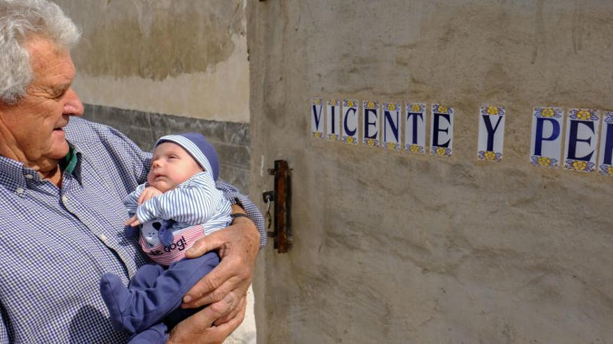 Vicente mira, con un gesto tierno, a su bisnieto nacido hace dos meses en la puerta de su vivienda en la huerta de Dolores.