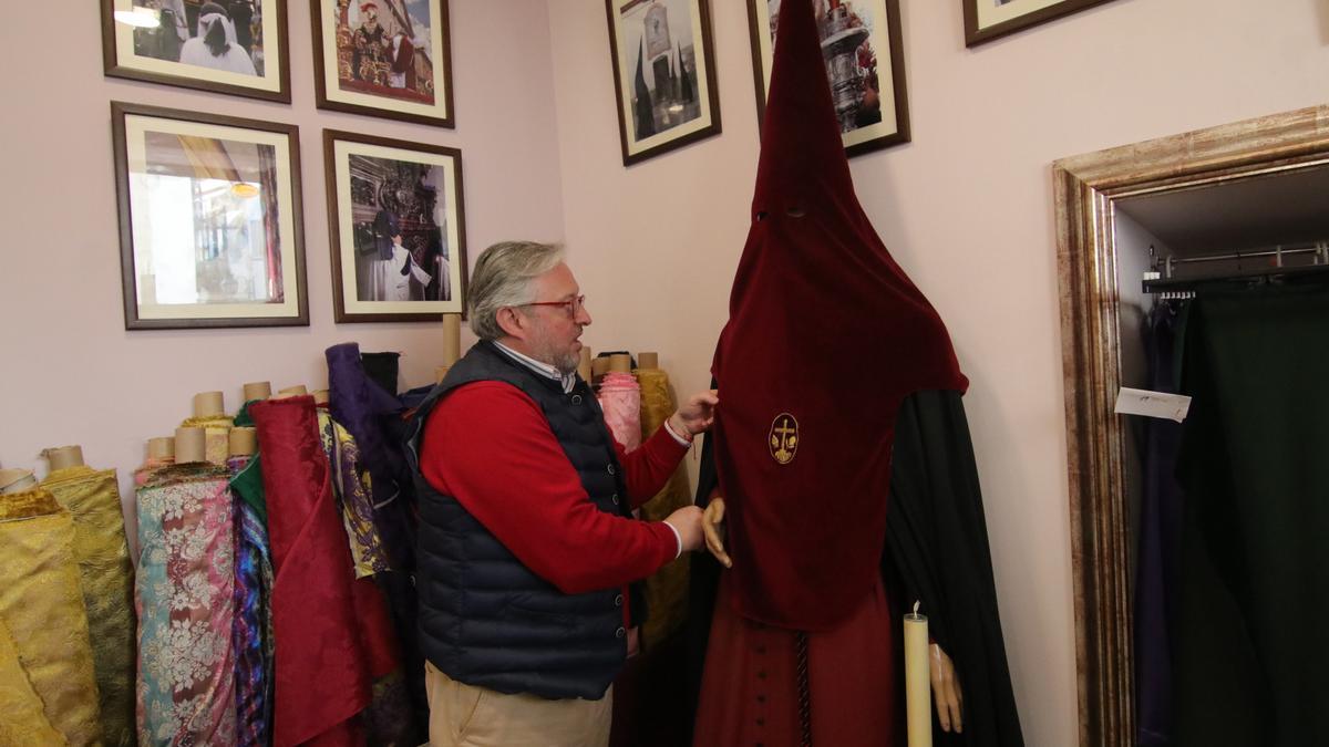 Juan Carlos Vizcaíno coloca una de las túnicas expuestas en su tienda.