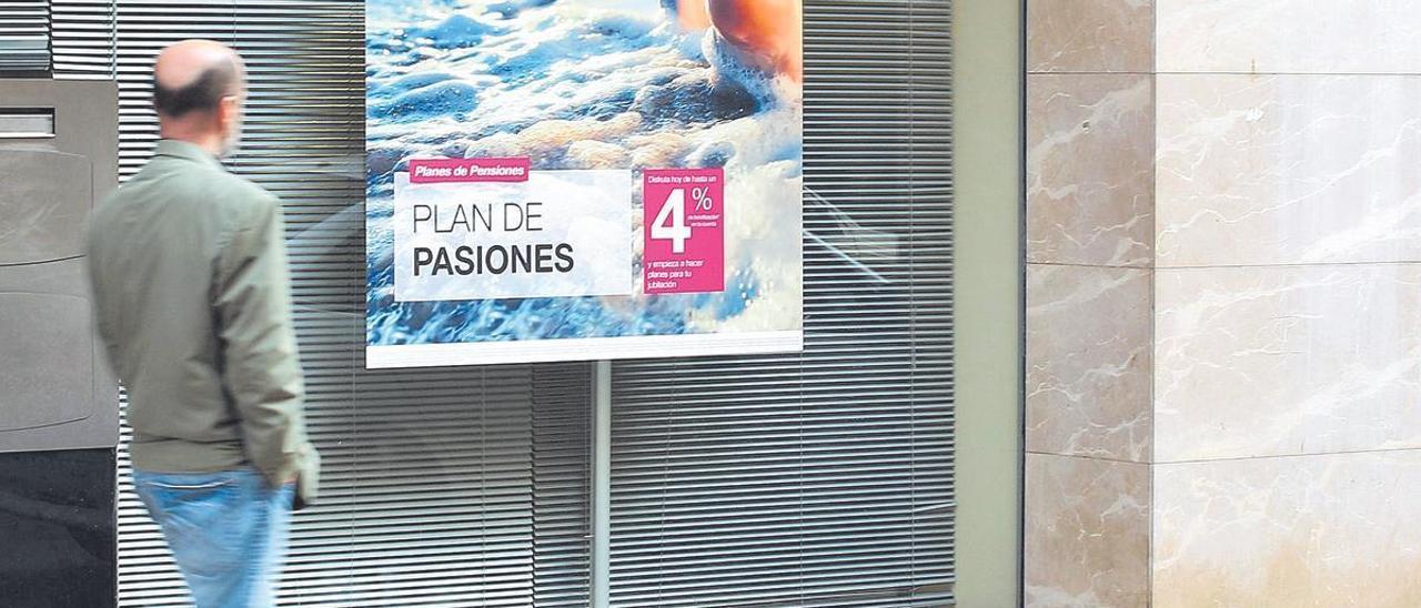 Un viandante pasa frente a una sucursal que publicita un plan de pensiones.