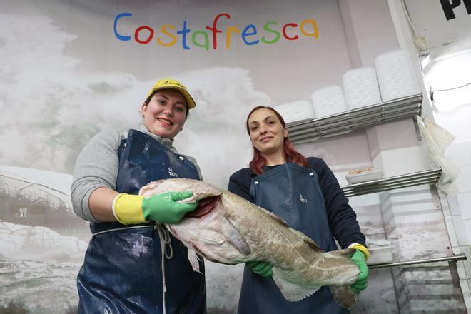 Laura e Ingrid, pescaderas de Costa Fresca, sujetando una pieza de pescado en su negocio.