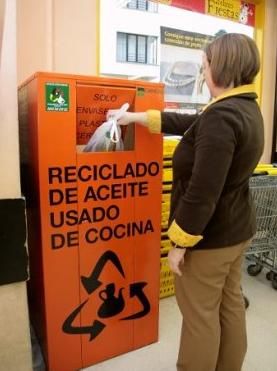 Una persona utiliza el contenedor naranja de reciclaje de aceites de cocina.