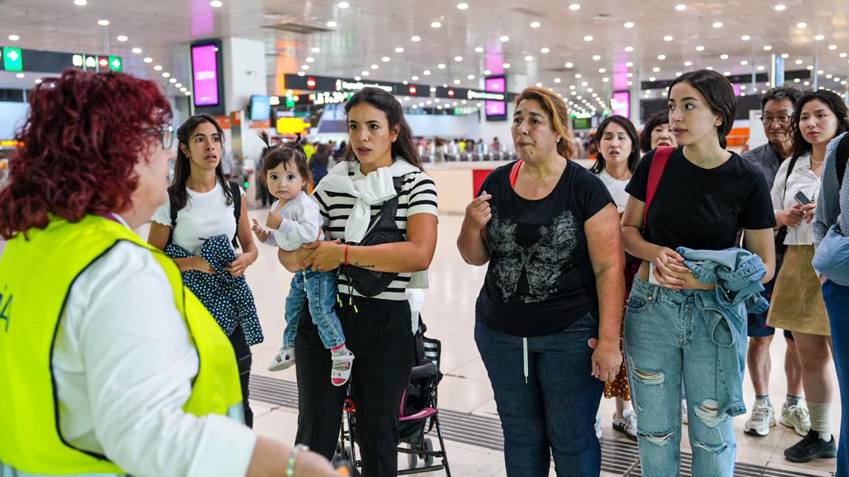 Una informadora de Renfe en la estación de Sants habla con usuarios tras el corte generalizado de Rodalies