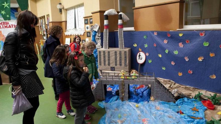 Asistentes a la exposición instalada en el colegio La Salle, con una recreación de una fábrica al fondo.