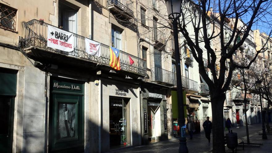 Un balcó de la Rambla on hi llueix una pancarta que reclama menys habitatges d&#039;ús turístic al Barri Vell de Girona