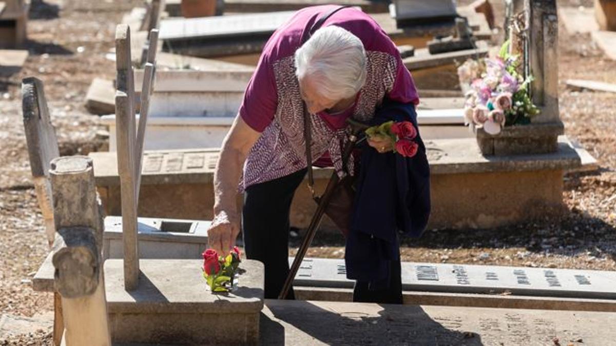 Una mujer pone flores a un difunto en el Cementerio General.