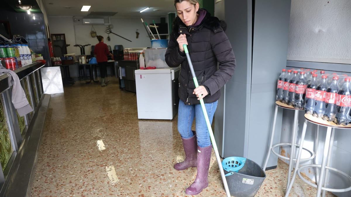 Una mujer achica agua de su negocio en uno de los municipios más afectados por las lluvias del domingo 28 de diciembre.