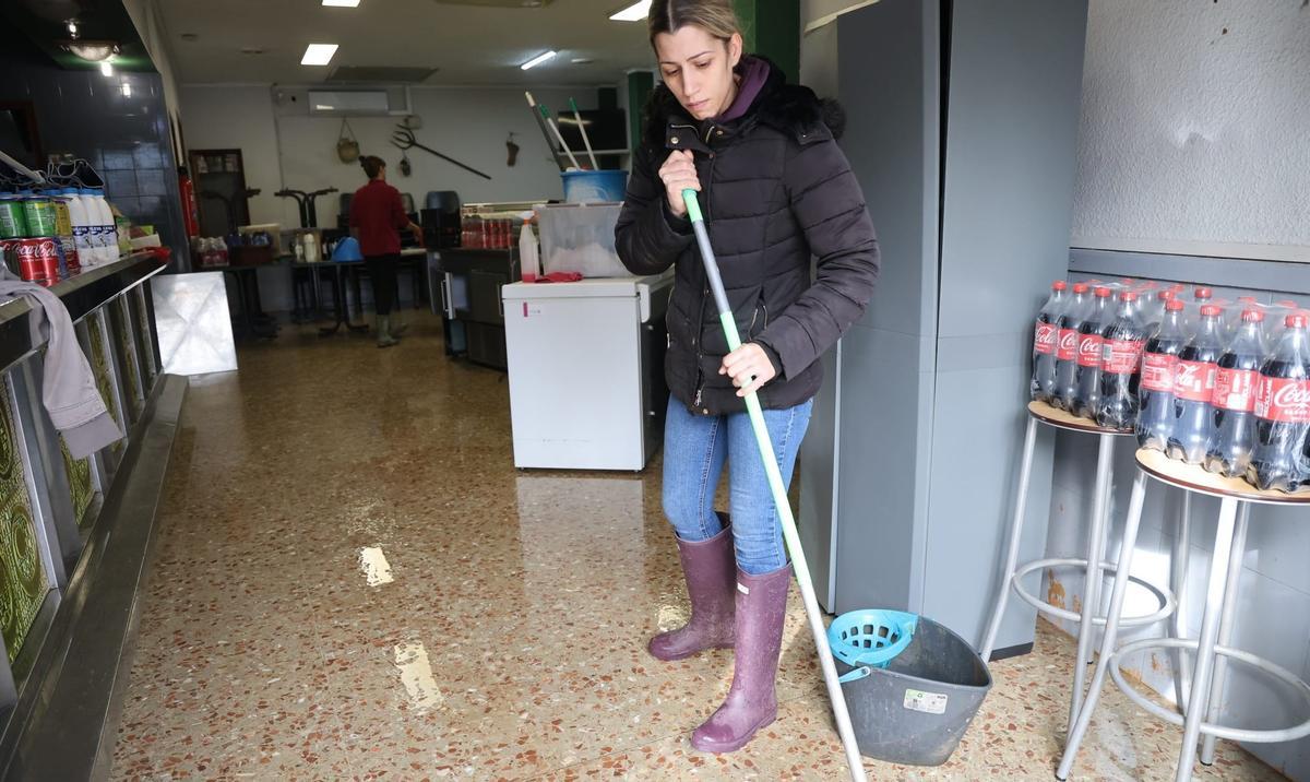 Una mujer achica agua de su negocio en uno de los municipios más afectados por las lluvias del domingo 28 de diciembre.