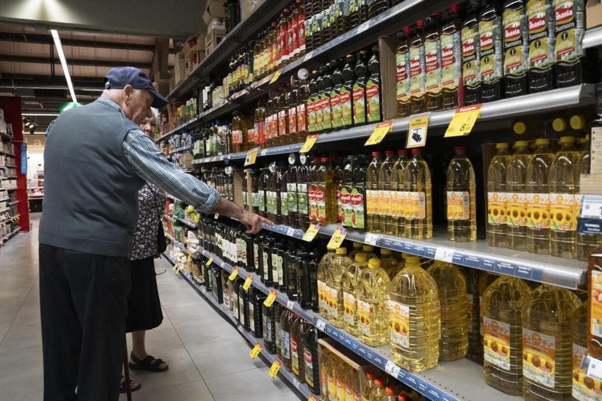 Un anciano comprueba los precios de distintos aceites de oliva en un supermercado.