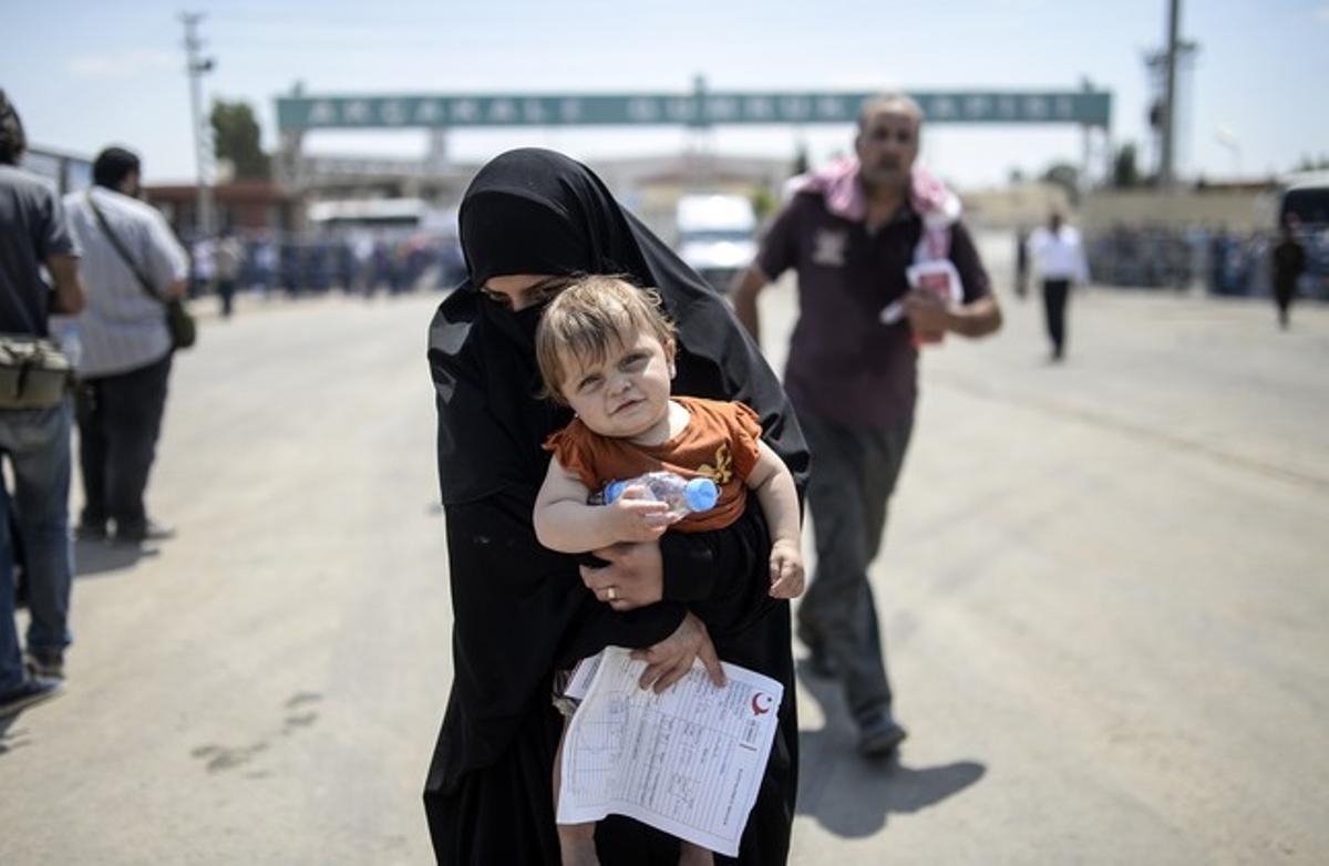 Una mujer siria cruza la frontera con Turquía.
