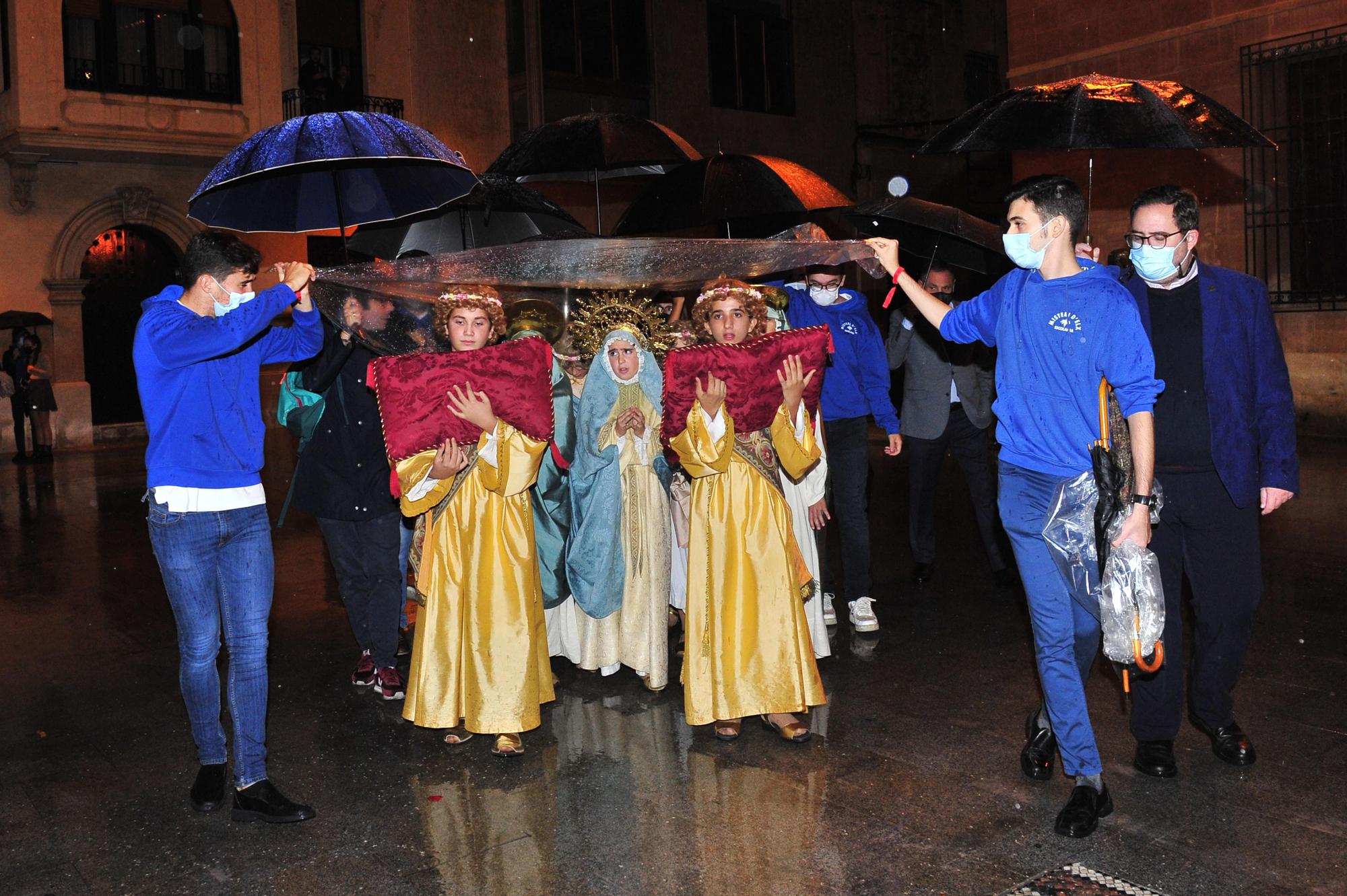 El cortejo de la Virgen protegiendose de la lluvia