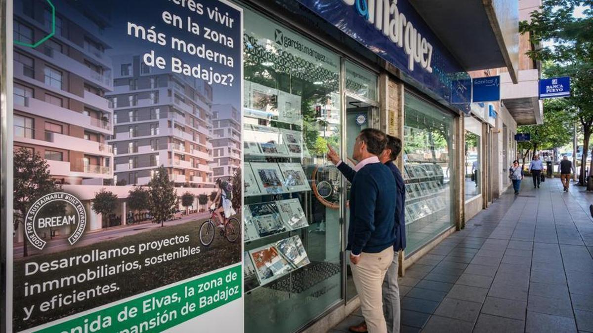 Dos posibles clientes miran las ofertas en el escaparate de una de las inmobiliarias de Badajoz.
