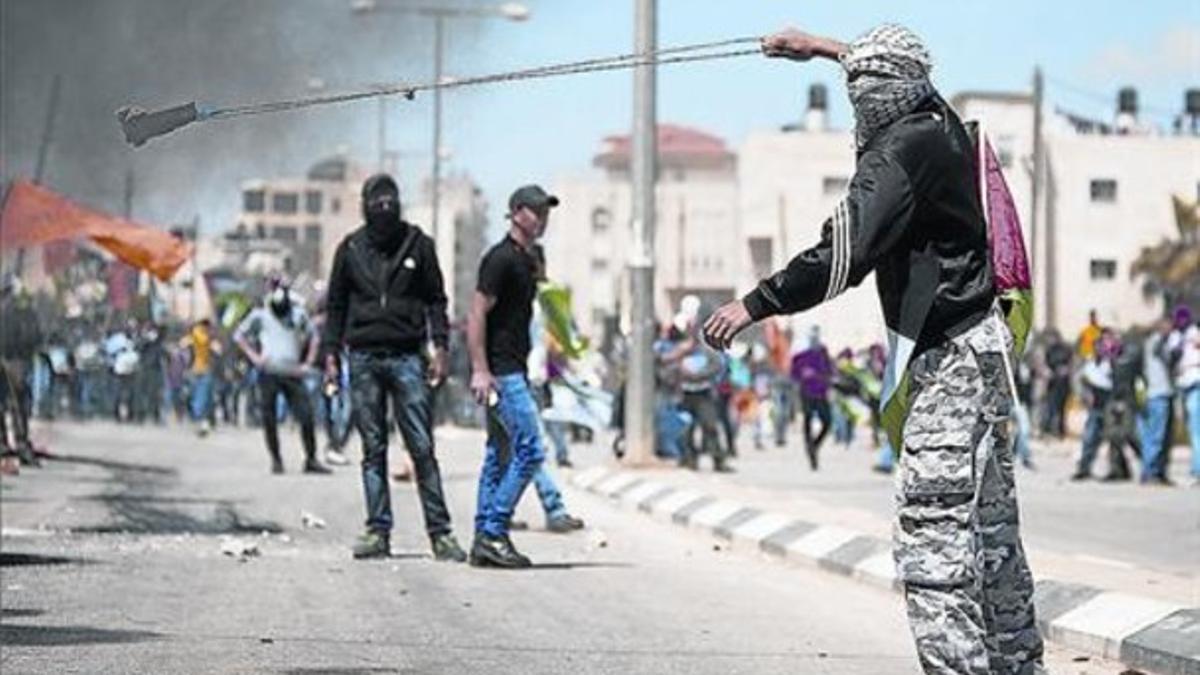 Un palestino lanza piedras contra soldados israelís exigiendo la liberación de presos, el viernes.