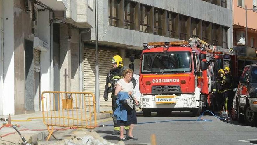 Bomberos con vecinos en el lugar del escape de gas. // Rafa Vázquez