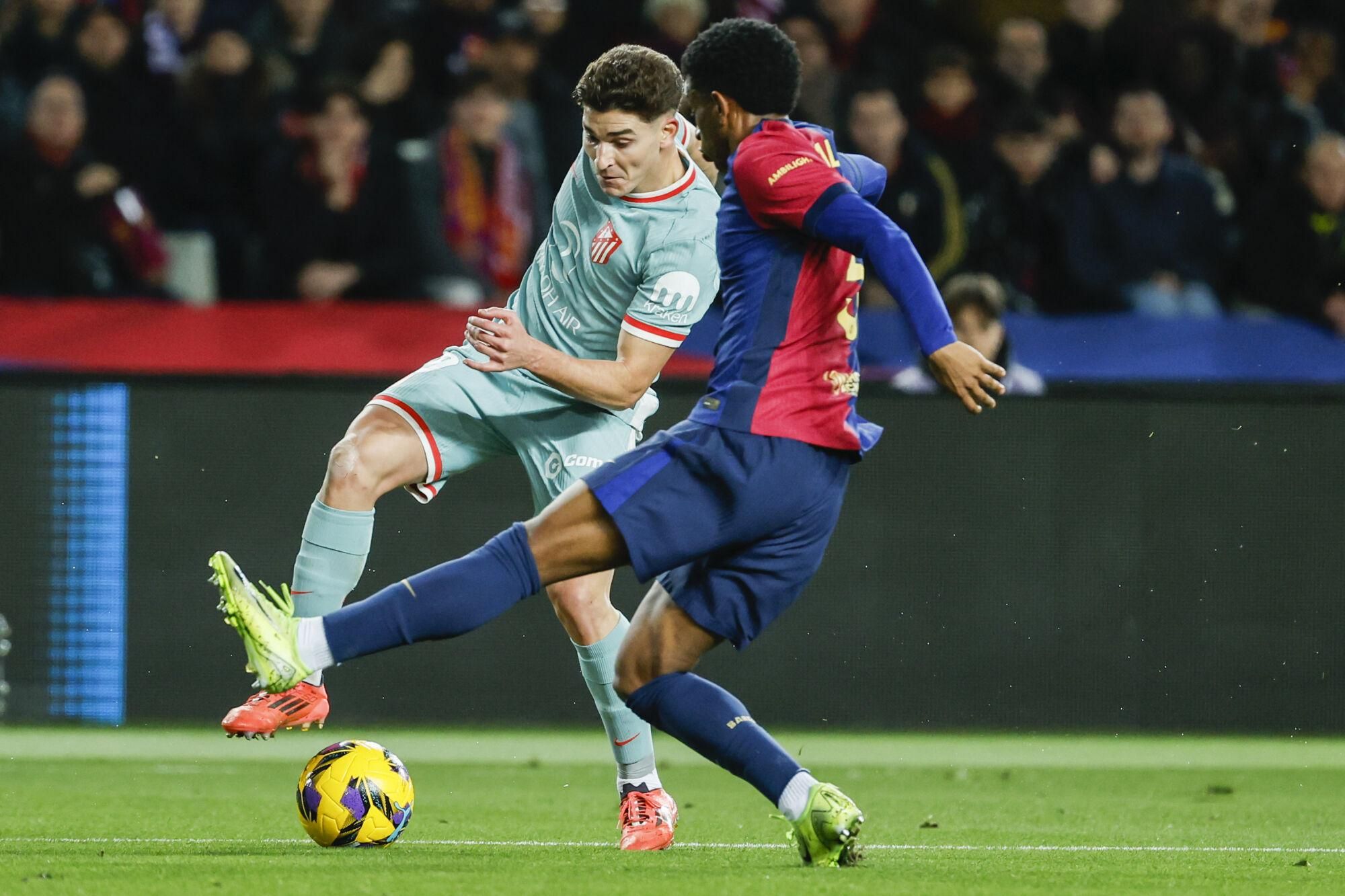 Atletico Madrid's Julian Alvarez, left, duels for the ball with Barcelona's Alejandro Balde during the Spanish La Liga soccer match between Barcelona and Atletico Madrid at the Lluis Companys Olympic Stadium in Barcelona, Spain, Saturday, Dec. 21, 2024. (AP Photo/Joan Monfort)