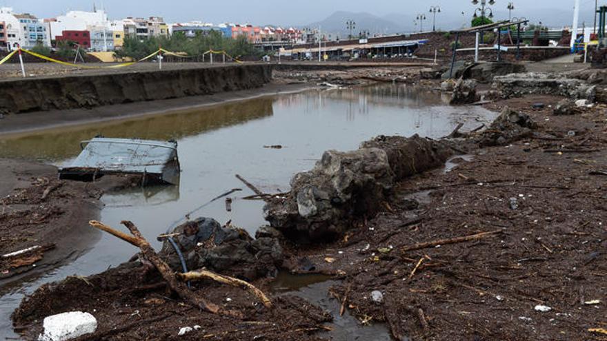 En primer término, un contenedor de basura arrastrado por el agua a la arena de Melenara, arrasada también por las escorrentías.