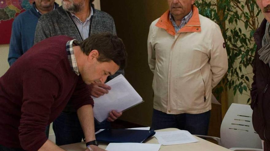 Julio Antuña firma el documento. Detrás, Alberto Tirador y Fernando Díaz Rañón.