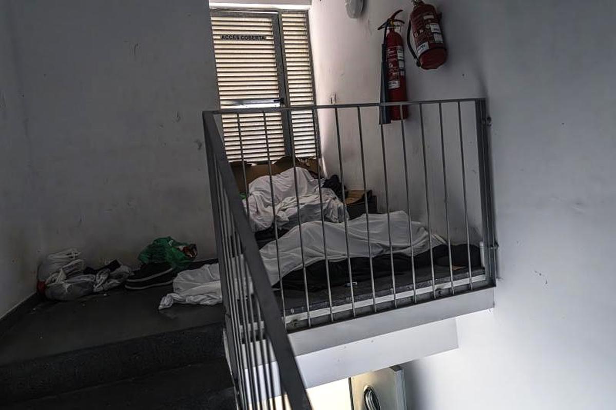 Dos personas duermen en unos colchones situados en un rellano en un edificio de la Agència de l'Habitatge de Catalunya de L'Hospitalet.