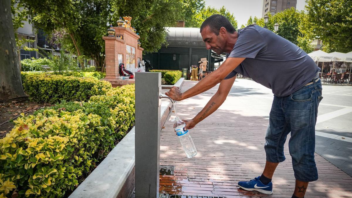 Una persona rellena una botella en una fuente del paseo de San Francisco de Badajoz.