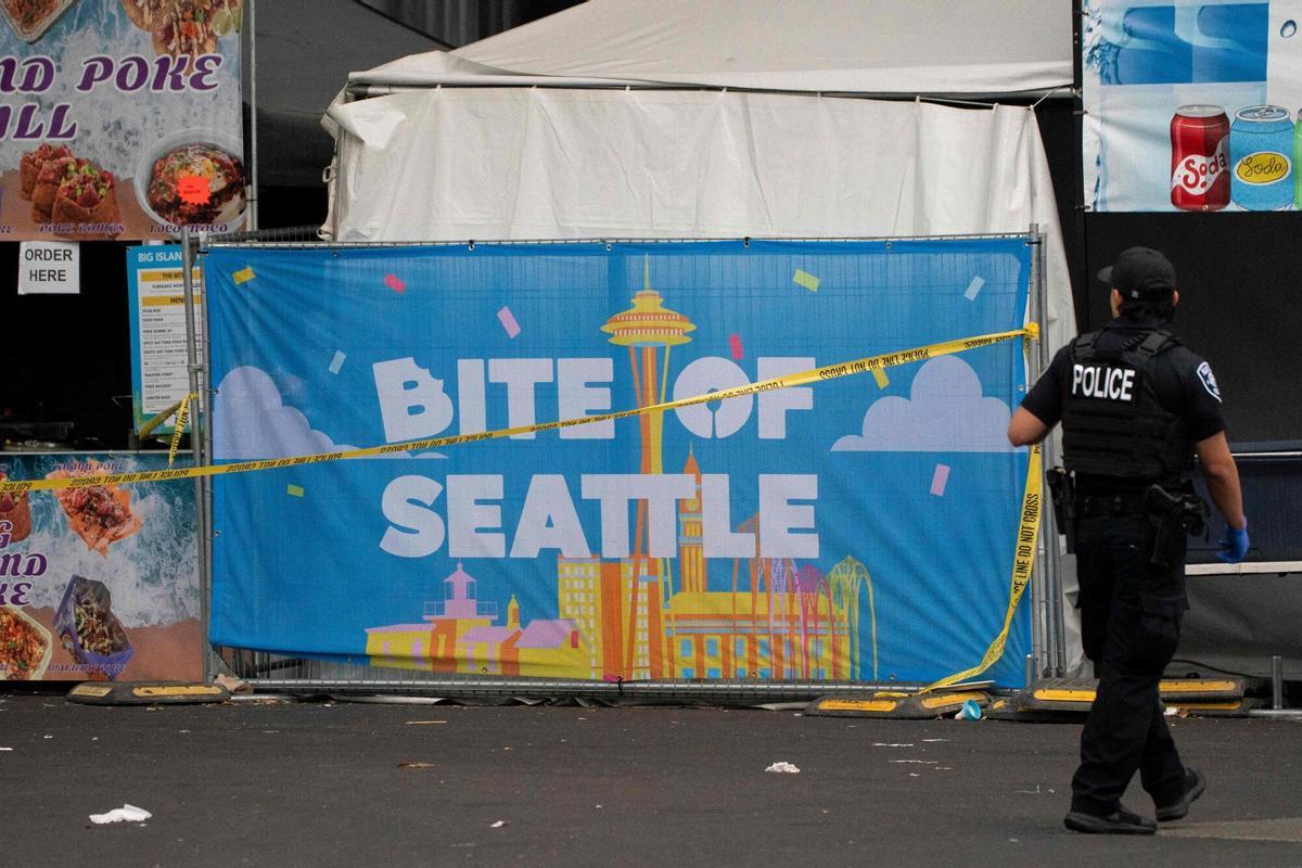 Un agente de policía camina junto a un cartel del festival Bite of Seattle tras el tiroteo masivo ocurrido durante el evento Un agente de policía camina junto a un cartel del festival Bite of Seattle tras el tiroteo masivo ocurrido durante el evento