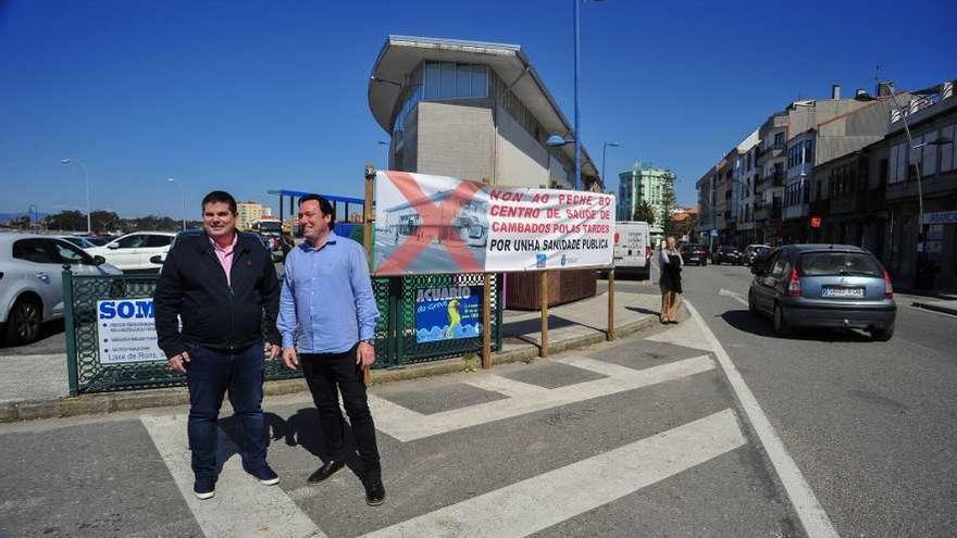 Xurxo Charlín y Constantino Cordal, junto a una pancarta de protesta en el centro de salud. // Iñaki Abella