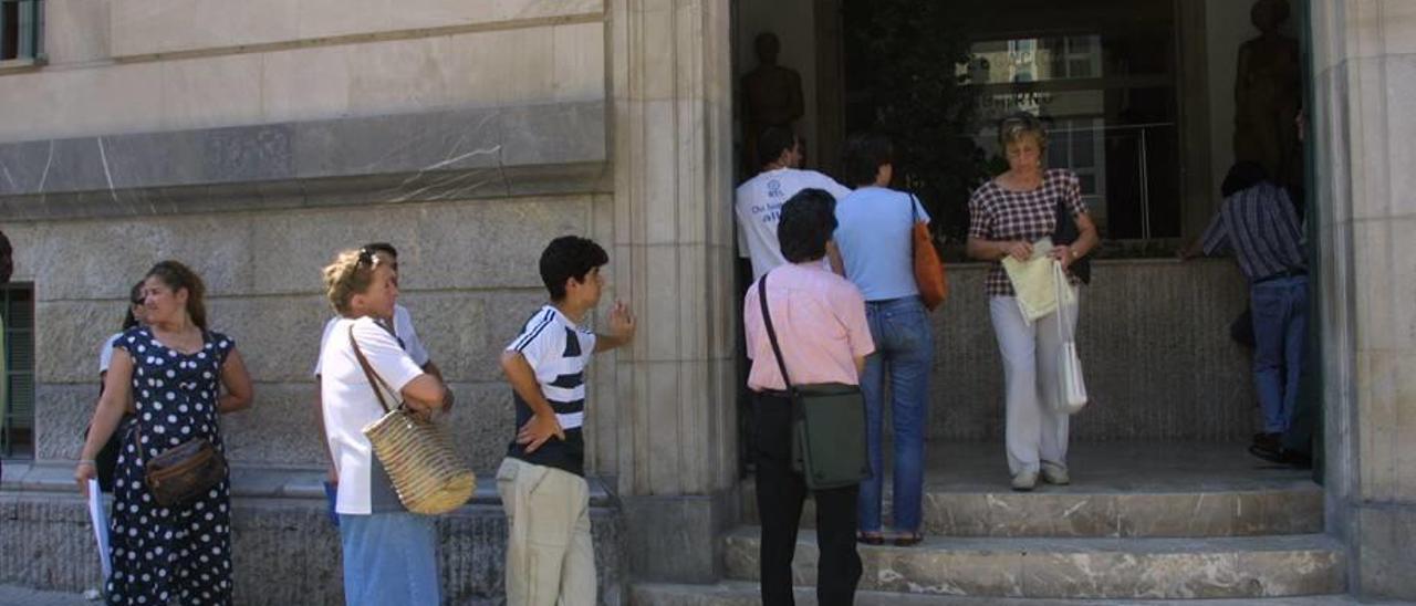 Inmigrantes haciendo cola ante la sede central de la delegación del Gobierno, en el centro de Palma.
