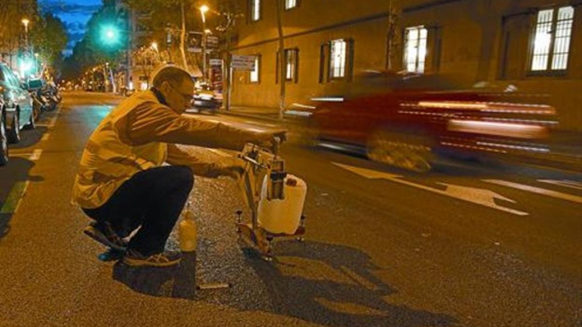 Un técnico comprueba si el líquido esparcido en la calle de la Indústria de Barcelona es demasiado resbaladizo para los coches, el martes.